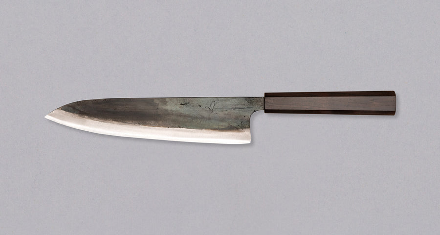 Kokugei Gyuto Aogami #1 Kuro-uchi Ebony 210 mm svestrani je japanski kuhinjski nož namijenjen pripremi mesa, ribe i povrća. Nož ima distalno suženu pozadinu i rustikalnu crnu kuro-uchi površinsku obradu koja odražava tradicionalnu estetiku ručno kovanih japanskih noževa.