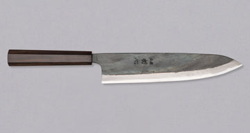 Kokugei Gyuto Aogami #1 Kuro-uchi Ebony 240 mm svestrani je japanski kuhinjski nož namijenjen pripremi mesa, ribe i povrća. Nož ima distalno suženu pozadinu i rustikalnu crnu kuro-uchi površinsku obradu koja odražava tradicionalnu estetiku ručno kovanih japanskih noževa.