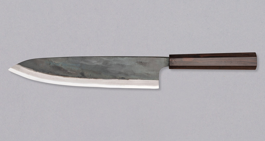 Kokugei Gyuto Aogami #1 Kuro-uchi Ebony 240 mm svestrani je japanski kuhinjski nož namijenjen pripremi mesa, ribe i povrća. Nož ima distalno suženu pozadinu i rustikalnu crnu kuro-uchi površinsku obradu koja odražava tradicionalnu estetiku ručno kovanih japanskih noževa.