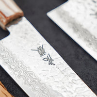 Kotetsu Santoku VG-10 Damascus 180 mm veliki svestrani je nož s vidljivim otiscima čekića i klasičnom japanskom (wa-style) drškom od tikovine. Oduševit će svakega koji cijene i estetski oblikovane kuhinjske posuđe.