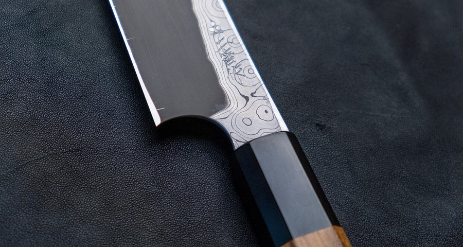 Nigara Kurozome Kiritsuke Yanagiba Aogami #2 Damascus 240 mm tradicionalni je japanski nož koji se koristi za pripremu ribe (osobito za sašimi i nigiri suši). Duga oštrica omogućuje lijepe i duge pokrete, a podrezan vršak precizan završetak reza.