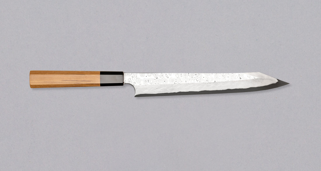 Nigara Kurozome Kiritsuke Yanagiba Aogami #2 Damascus 240 mm tradicionalni je japanski nož koji se koristi za pripremu ribe (osobito za sašimi i nigiri suši). Duga oštrica omogućuje lijepe i duge pokrete, a podrezan vršak precizan završetak reza.