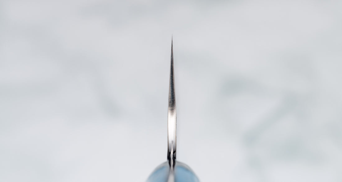 Choil. Nigara Santoku SG2 Migaki Tsuchime Turquoise 180 mm višenamjenski je japanski kuhinjski nož, pogodan za pripremu mesa, ribe i povrća. Jezgra od SG2 praškastog čelika i hamaguri presjek profila osiguravaju dugotrajnu oštrinu i minimalno održavanje. 