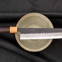 Tsunehisa Kiritsuke AS Kuro-uchi 240 mm je odličan ručno kovan nož sa crnom Kuro-uchi zaštitnom patinom i tragovima čekića. Oblik oštrice će odgovarati svima koji traže svestran nož za pripremu većih komada mesa, rezanje ribe i sjeckanje povrća. Nož je jednostavan za brušenje i održavanje.