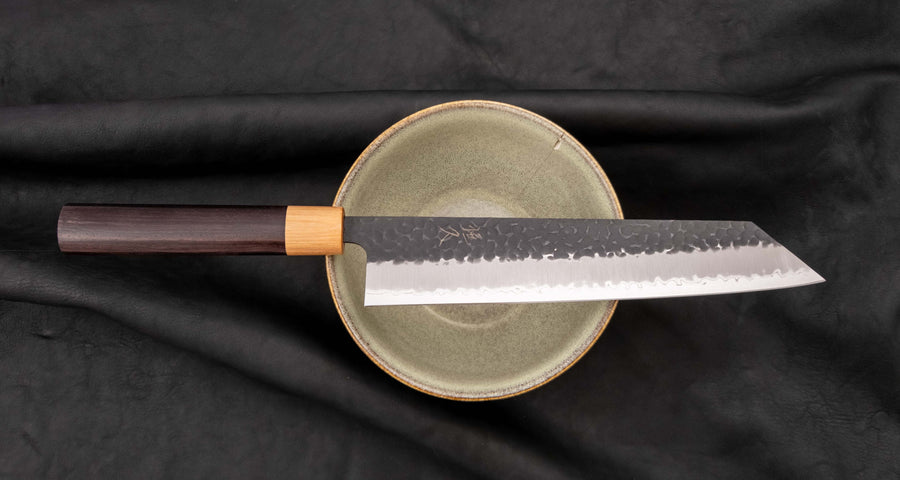 Tsunehisa Kiritsuke AS Kuro-uchi 240 mm je odličan ručno kovan nož sa crnom Kuro-uchi zaštitnom patinom i tragovima čekića. Oblik oštrice će odgovarati svima koji traže svestran nož za pripremu većih komada mesa, rezanje ribe i sjeckanje povrća. Nož je jednostavan za brušenje i održavanje.