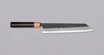 Tsunehisa Kiritsuke AS Kuro-uchi 240 mm je odličan ručno kovan nož sa crnom Kuro-uchi zaštitnom patinom i tragovima čekića. Oblik oštrice će odgovarati svima koji traže svestran nož za pripremu većih komada mesa, rezanje ribe i sjeckanje povrća. Nož je jednostavan za brušenje i održavanje.