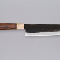 Ova oštrica Yoshida Nakiri Kyusyu SUJ-2 Kuro-uchi 165 mm [Rosewood-Cedar] iz kovačnice Yoshida Hamono ima drško od palisandra i drva cedrovine. Oštricu možete nabaviti također bez drške. Oštrica je kovana od Suj-2 čelika, tvrdoće 64 HRC, jednostavna za brušenje. Ima razvijenu tamnu patinu koja štiti oštricu.